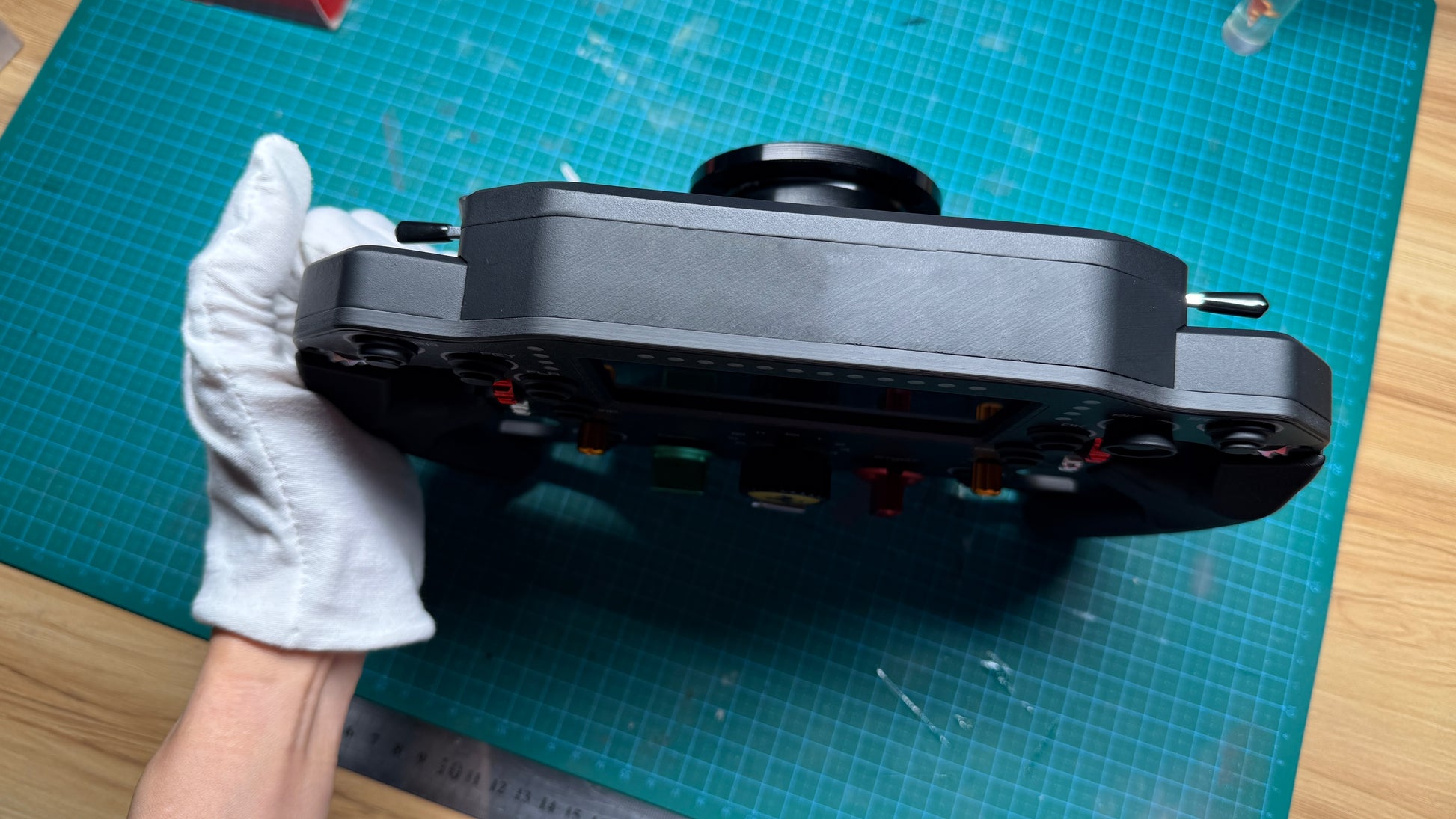 Ferrari 499P endurance sim racing wheel bottom edge view revealing the quick-release boss and underside cabling channel of the carbon fiber chassis.