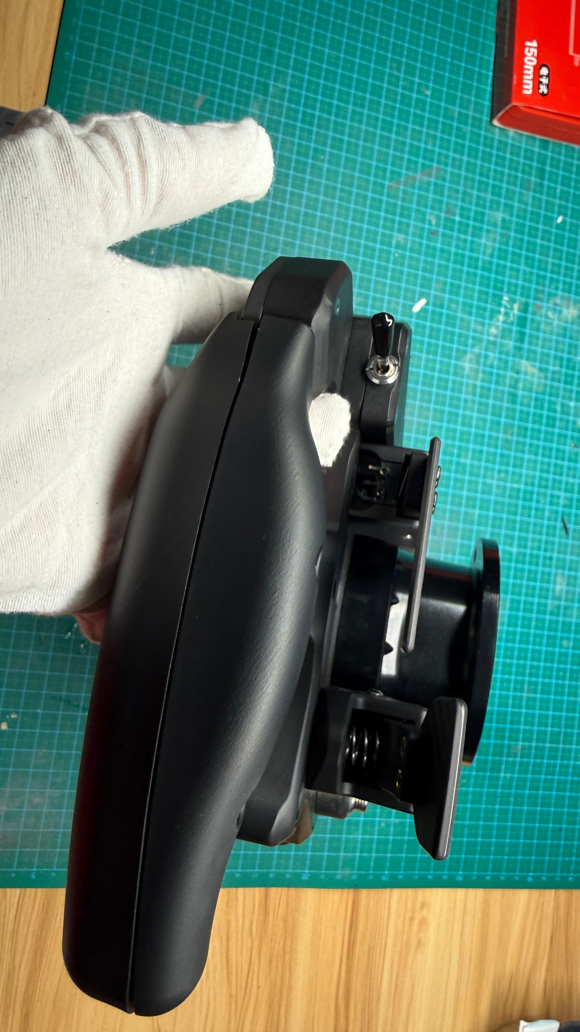 Ferrari 499P endurance sim racing wheel side grip profile showing the contoured rubberized hand grip and a top-mounted toggle switch on the front panel.