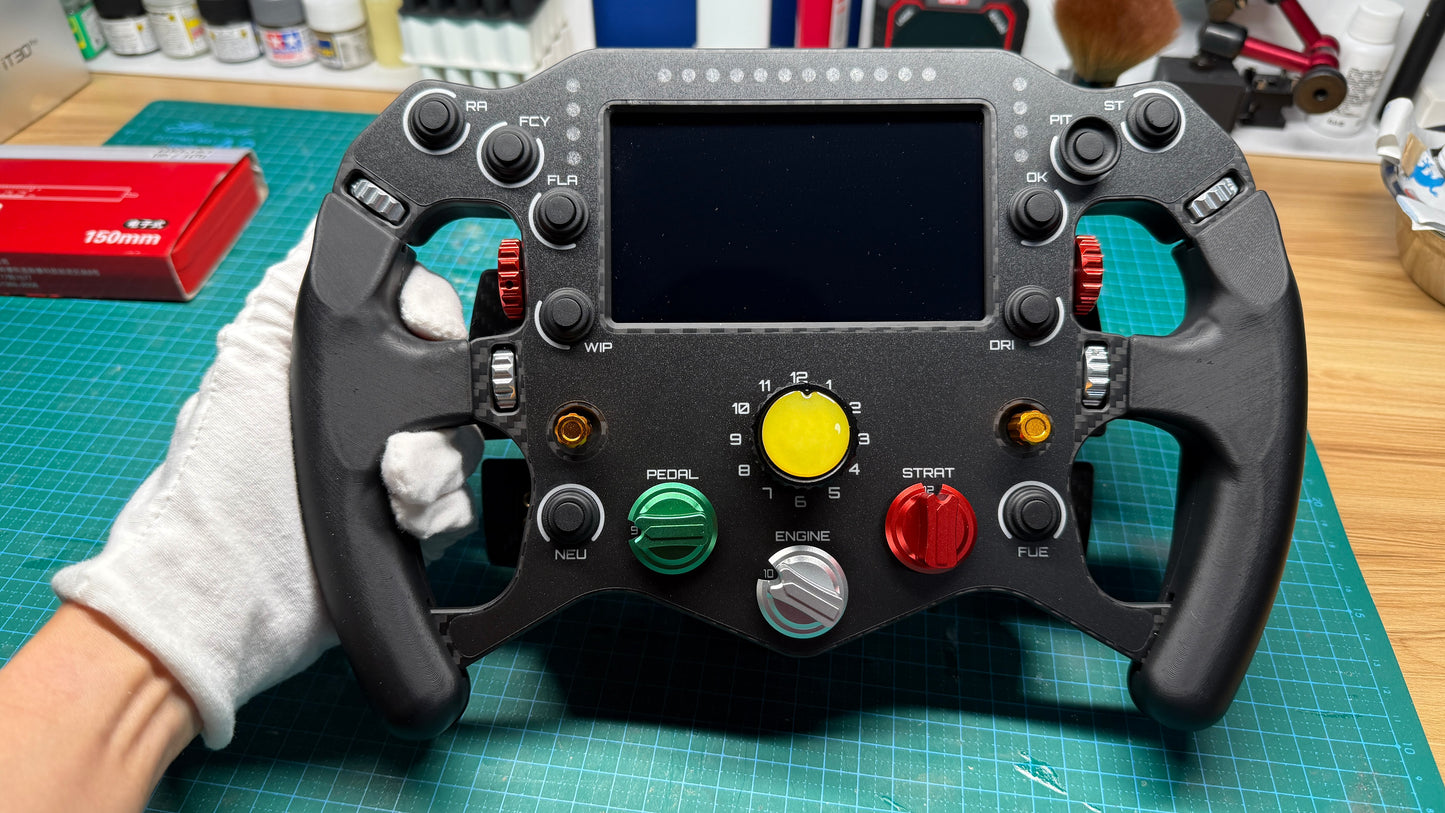 Ferrari 499P endurance sim racing wheel held in gloved hands, 5-inch telemetry display lit area with yellow center rotary and function switches across the front panel.
