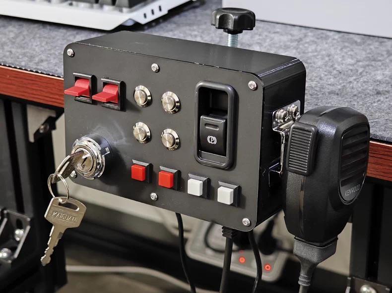 Truck simulator button box controller with ignition key, parking brake switch and handheld microphone mounted on desk for ETS2 and American Truck Simulator